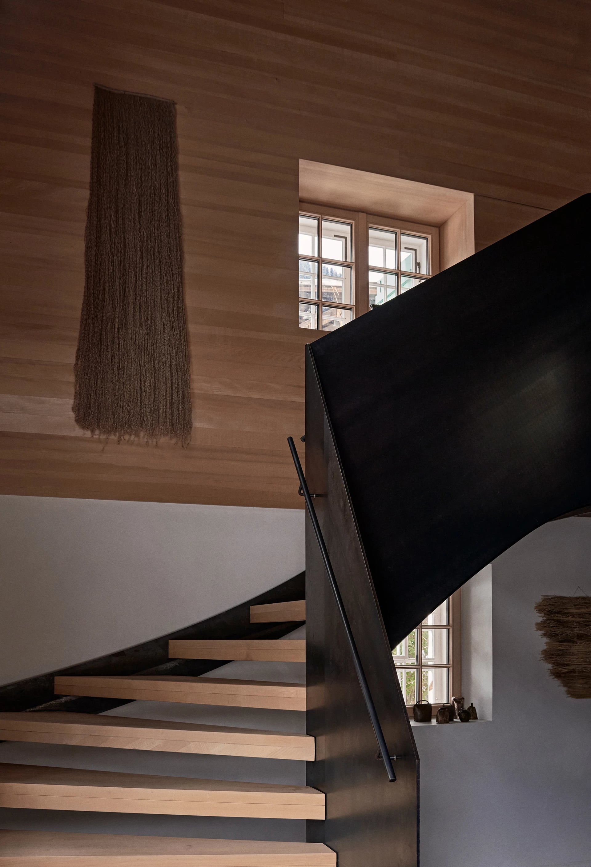 Living area with modern steel staircase and timber walls